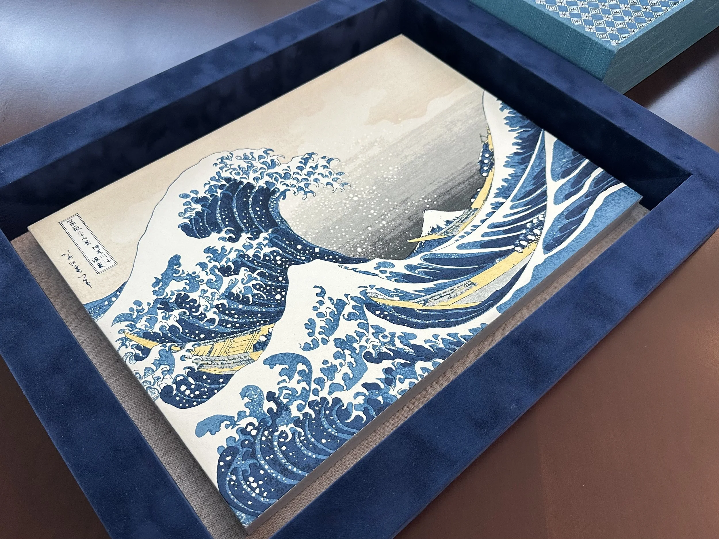 A traditional Japanese woodblock print titled "The Great Wave off Kanagawa" depicting large blue waves crashing with Mount Fuji in the background.