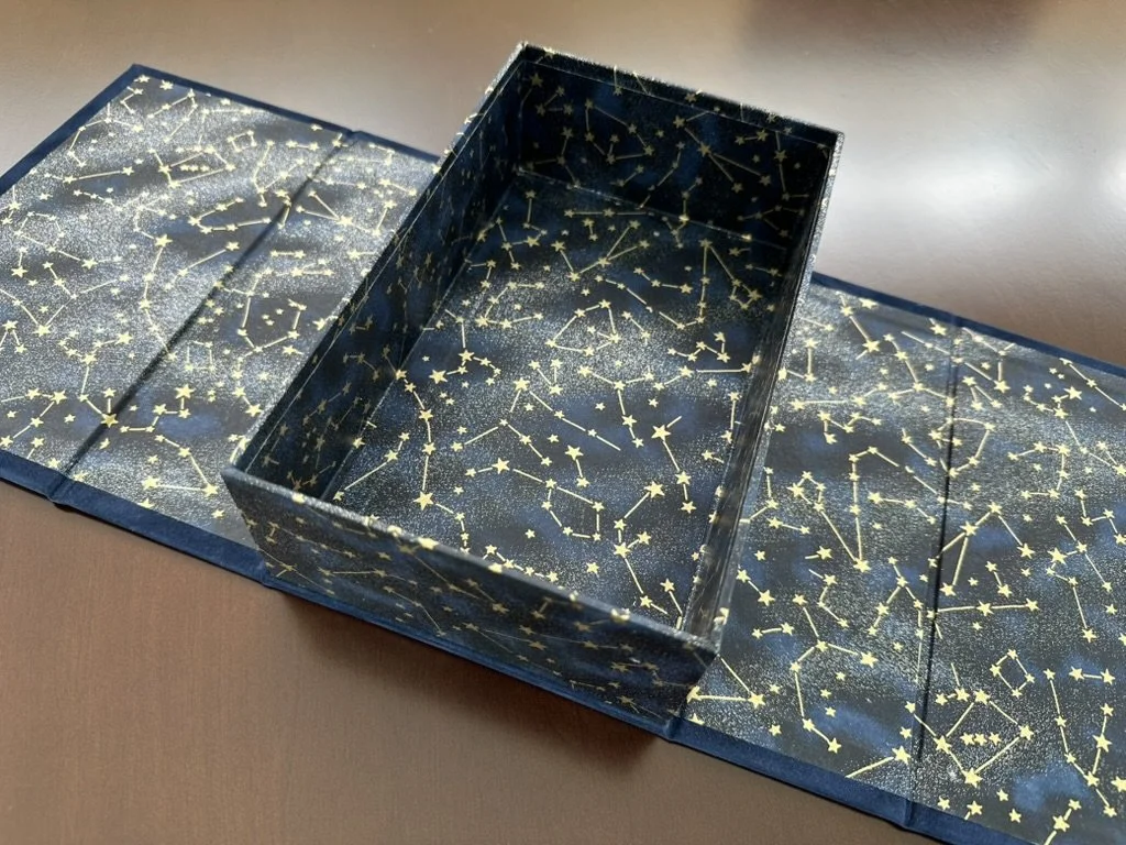 Open decorative box with a star and constellation pattern on inside and outside.