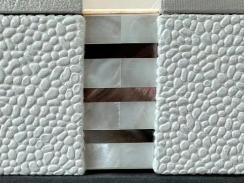 A close-up of a stone wall with three horizontal metallic strips in the middle.