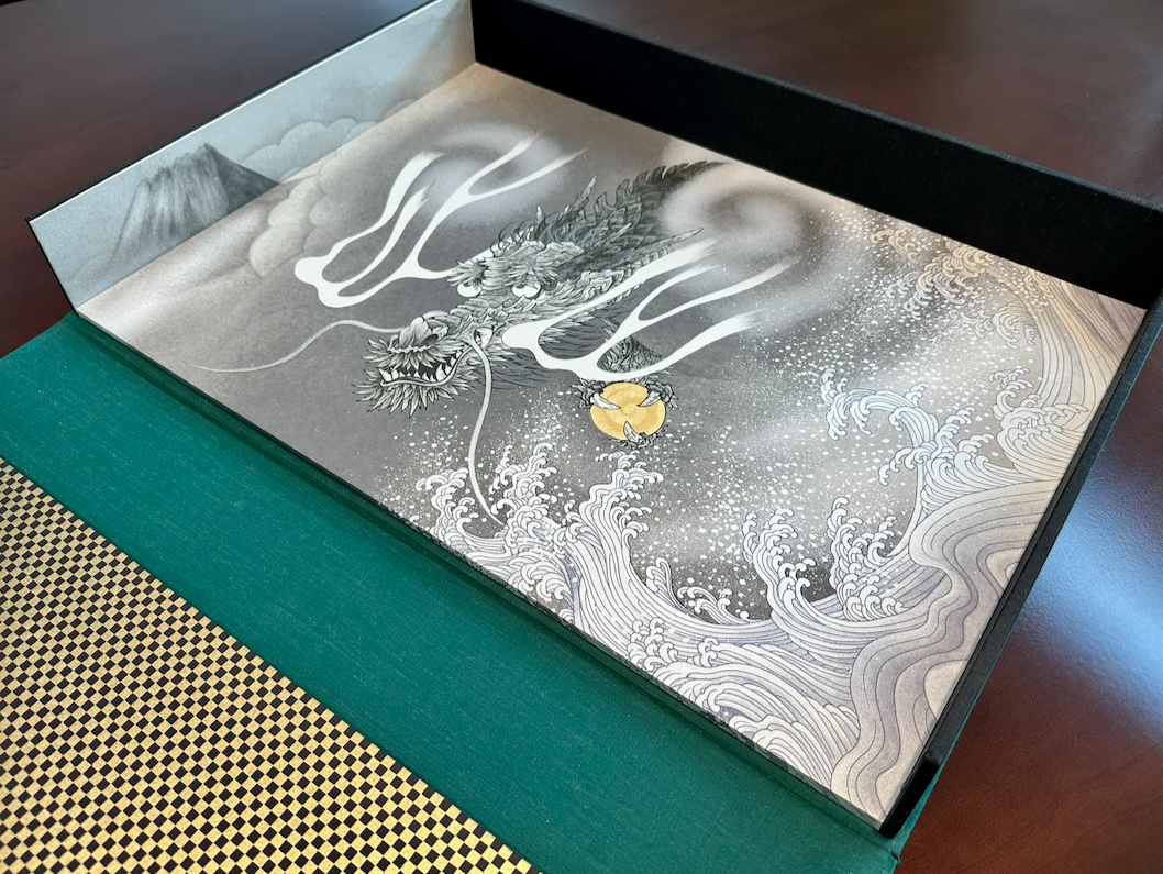 A detailed illustration of a dragon breathing smoke, with waves and clouds in the background, in a traditional Asian art style, inside a presentation box.