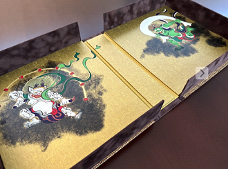 Decorative foldable screen featuring traditional Japanese artwork with dragons and clouds on a gold background.