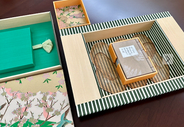 Various jewelry and decorative items in decorated boxes, including a jewelry card and a box with a clear lid and patterned design.