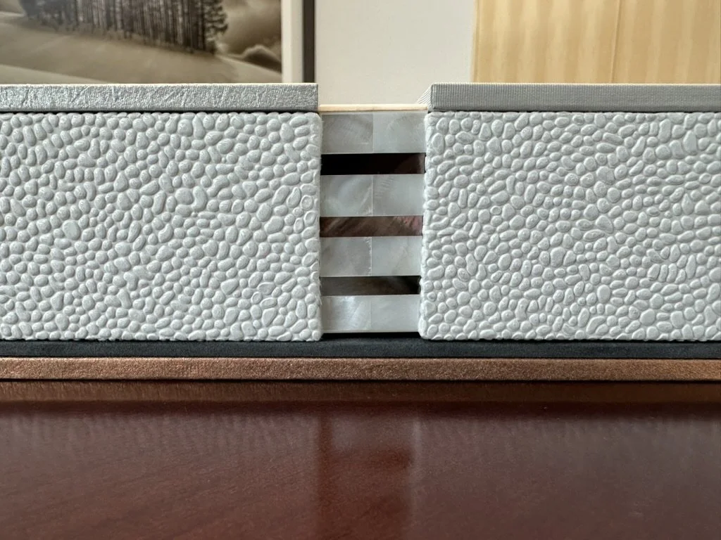 Close-up of two textured, grayish concrete blocks with a gap between them, revealing horizontal strips of a reflective material underneath.