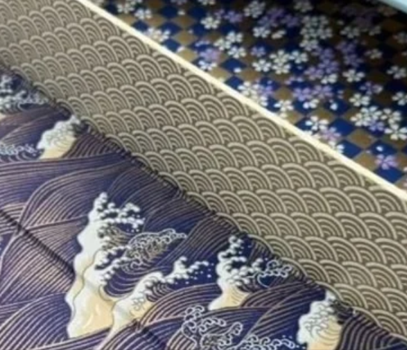 Close-up of traditional Japanese fabric with wave patterns and mountain scenery.