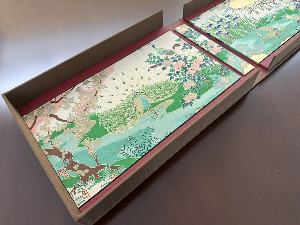 Set of Japanese-style paintings in a box, featuring a peacock, cherry blossoms, and traditional landscape scenes.