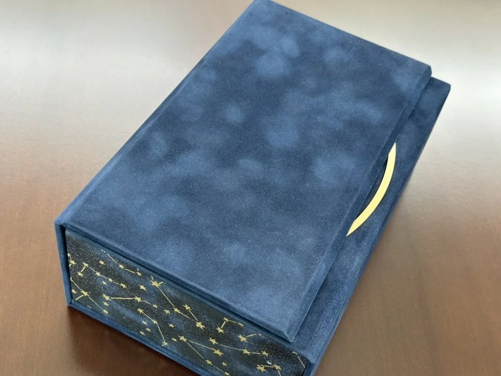 A blue box with a star and constellation pattern on the side, sitting on a wooden surface.