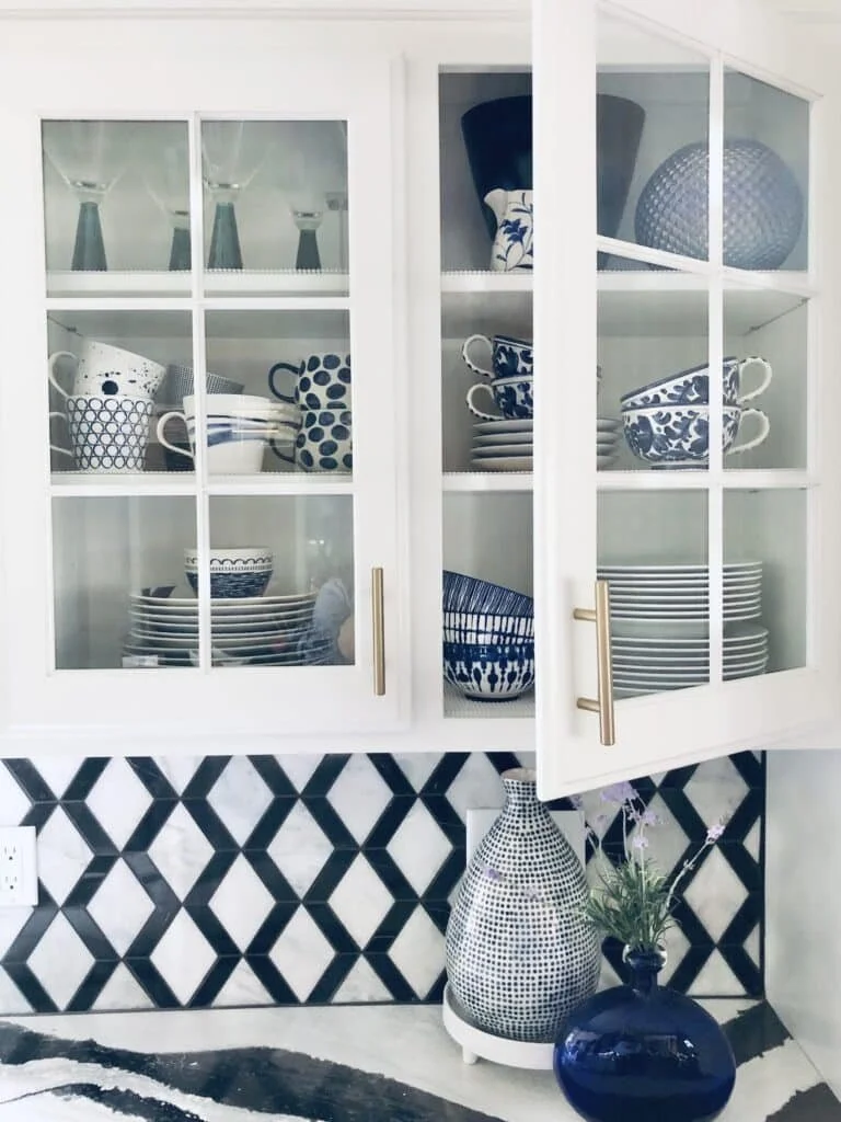 Illuminate your kitchen with glass cabinet inserts showcasing a stunning display of beautiful blue dishes, seamlessly marrying practical storage with aesthetic elegance.