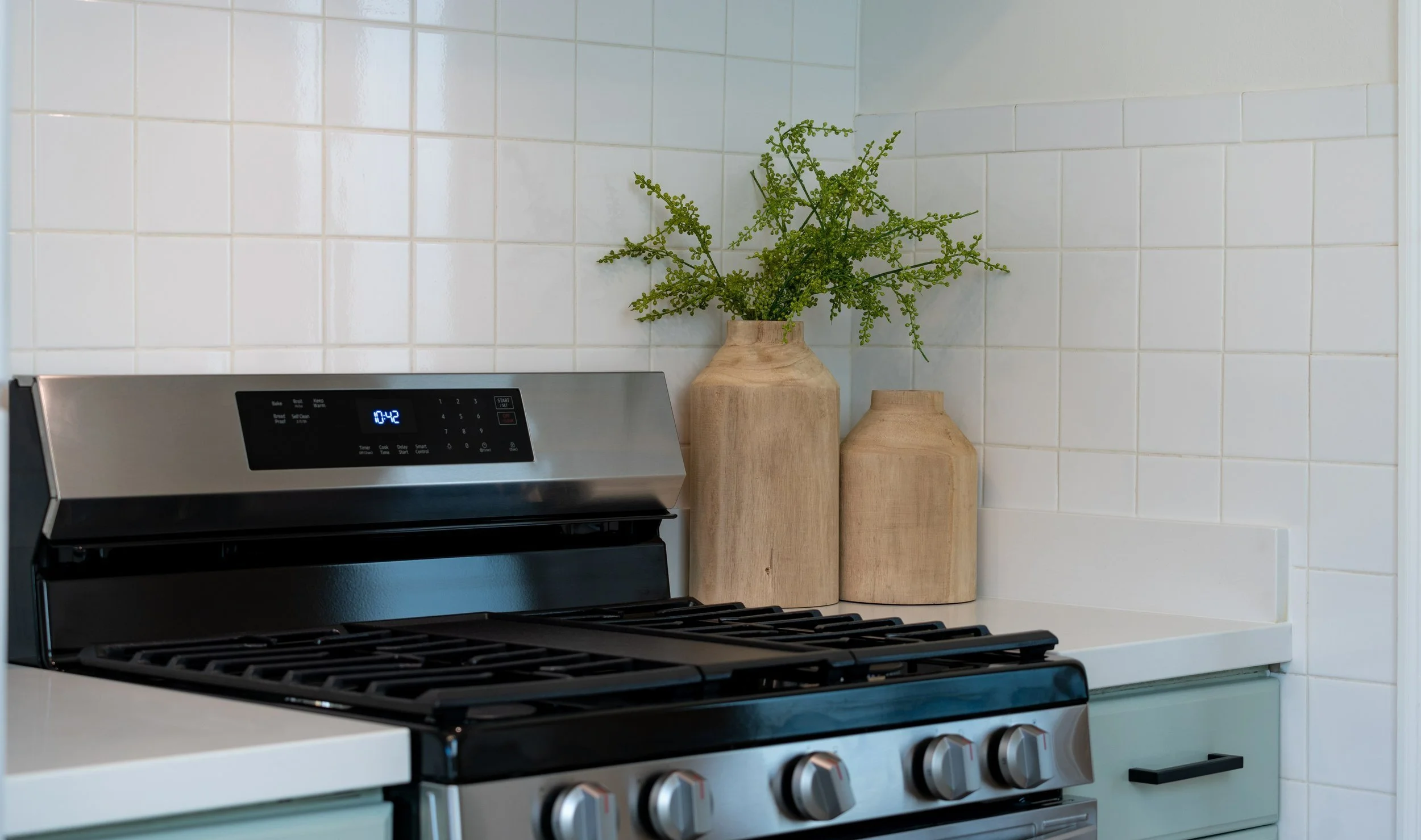 In this kitchen, a square grid white tile backsplash creates a clean and contemporary aesthetic. The simple yet elegant design enhances the space, offering a timeless backdrop that effortlessly complements various kitchen styles.