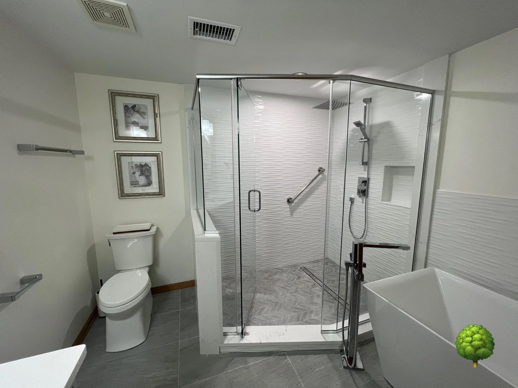 Modern bathroom with glass shower, bathtub, toilet, and framed artwork on wall.