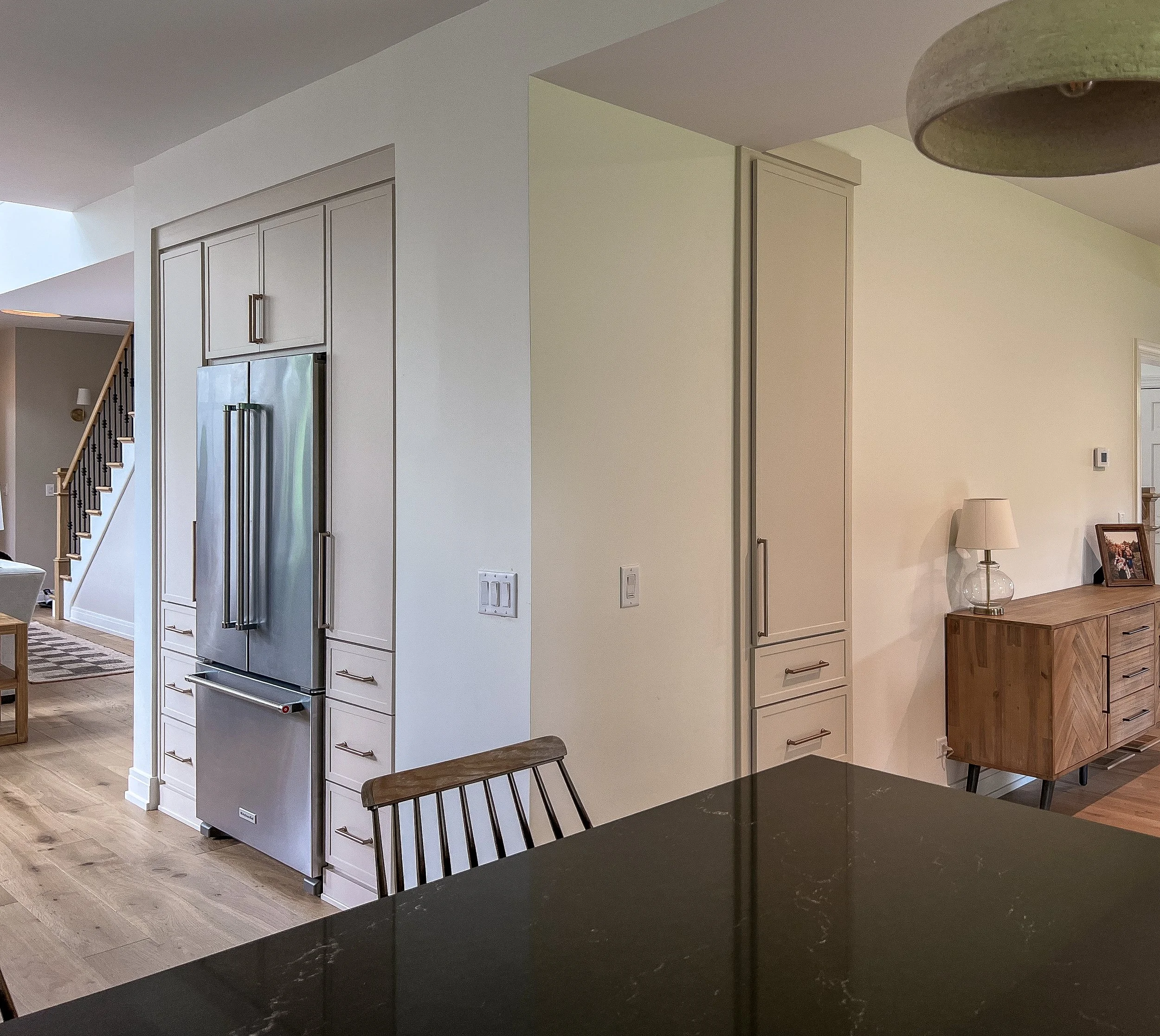 Integrated Wall Storage & Surround  |  Maximize floor space with custom cabinetry built directly into the home's architecture. This layout features a flush refrigerator enclosure flanked by deep storage drawers and a separate, recessed pantry tower. 