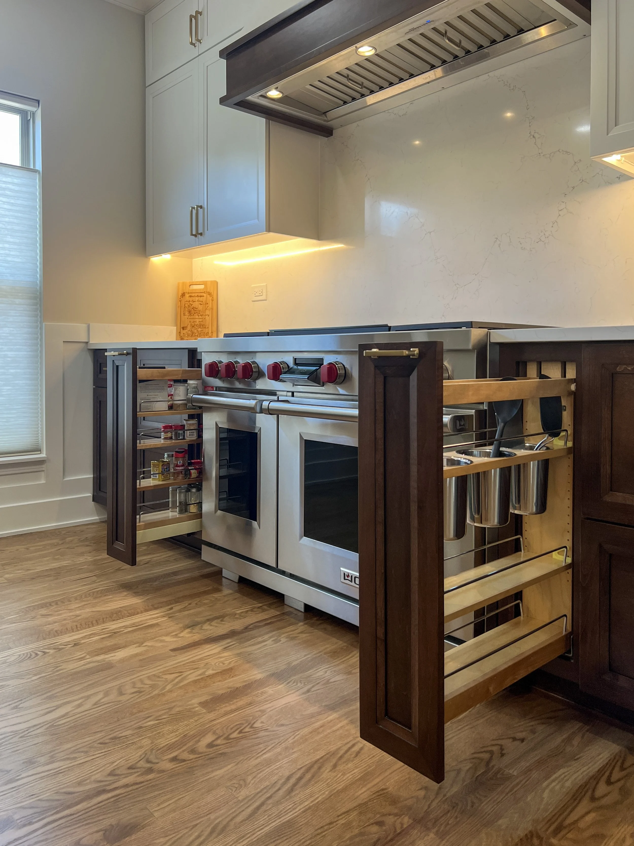 Dedicated Cooking Zones: Spice Rack & Utensil Pull-Outs  |  Streamline your cooking process. These custom base cabinet pull-outs ensure that everything you need is right next to the range. Featuring a multi-tiered spice pull-out on the left and a hig