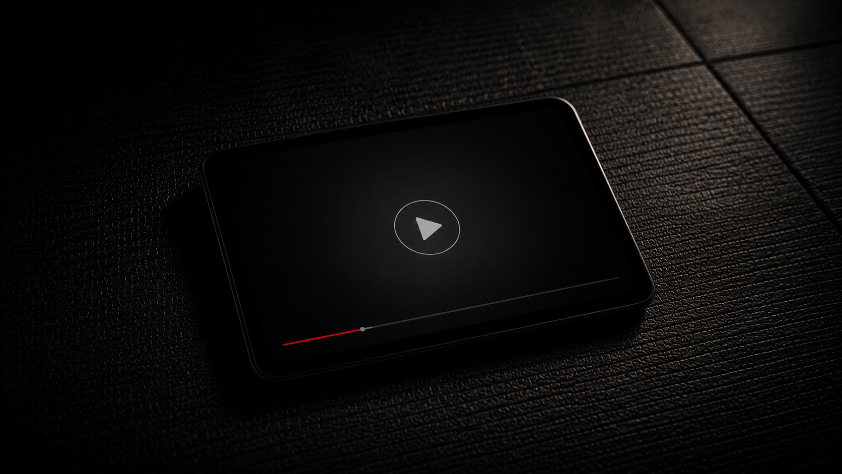A dark smartphone playing a video with a pause button at the center, lying on a textured black surface.