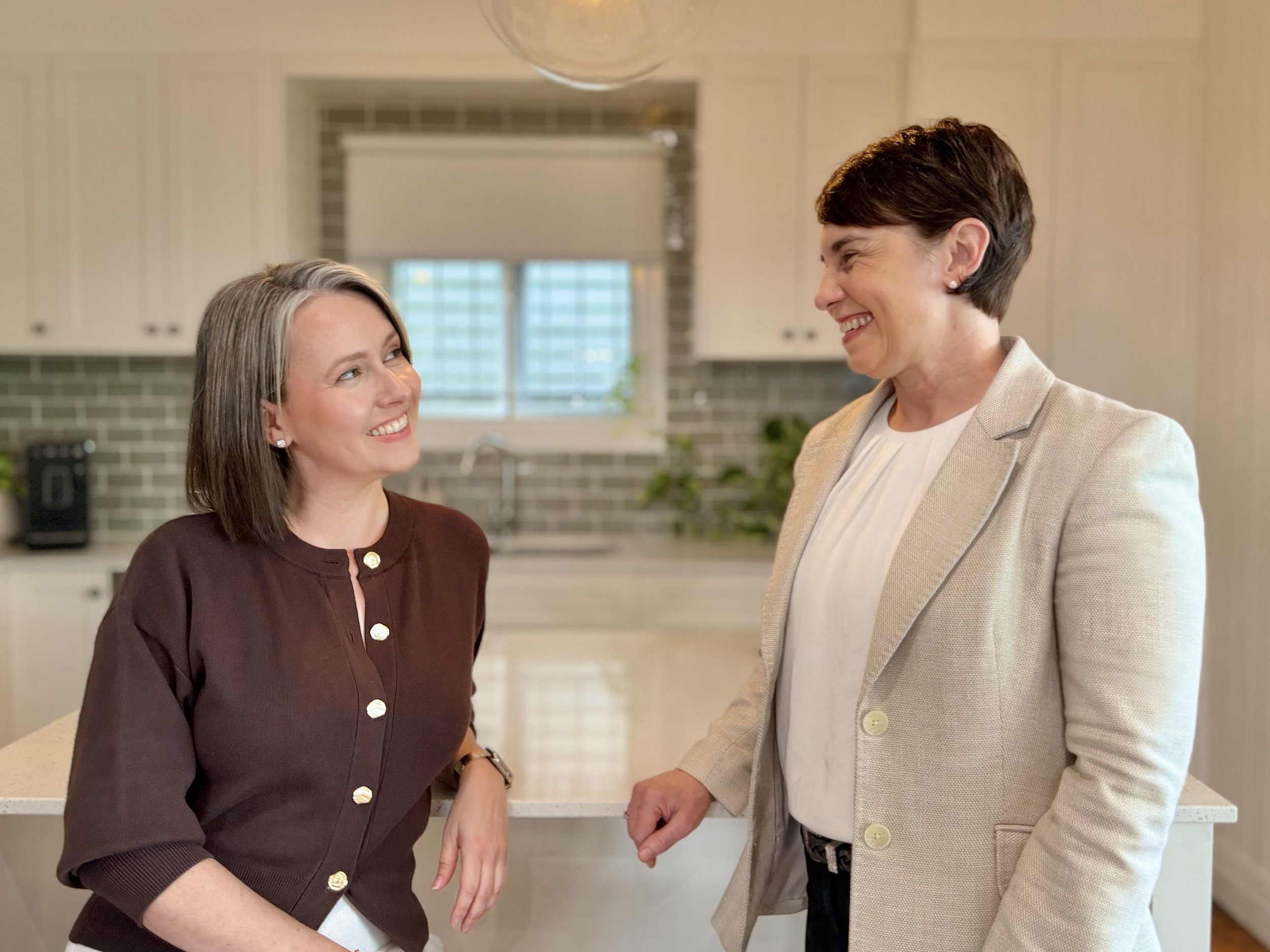 Karrie Jardine and Dr Julie Cichero in a kitchen, looking and smiling at each other.