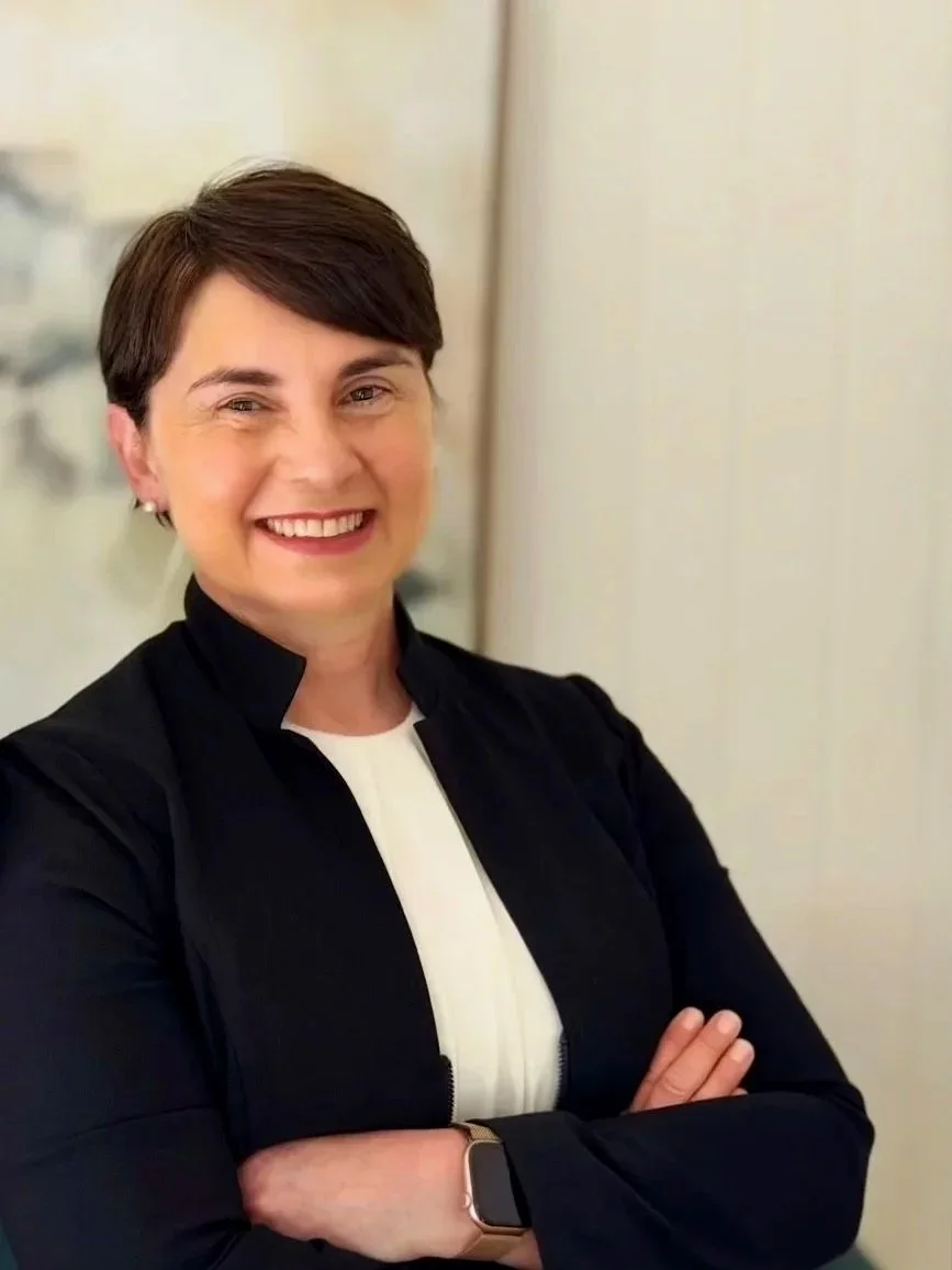 Dr Julie Cichero standing in an office, smiling with her arms crossed.