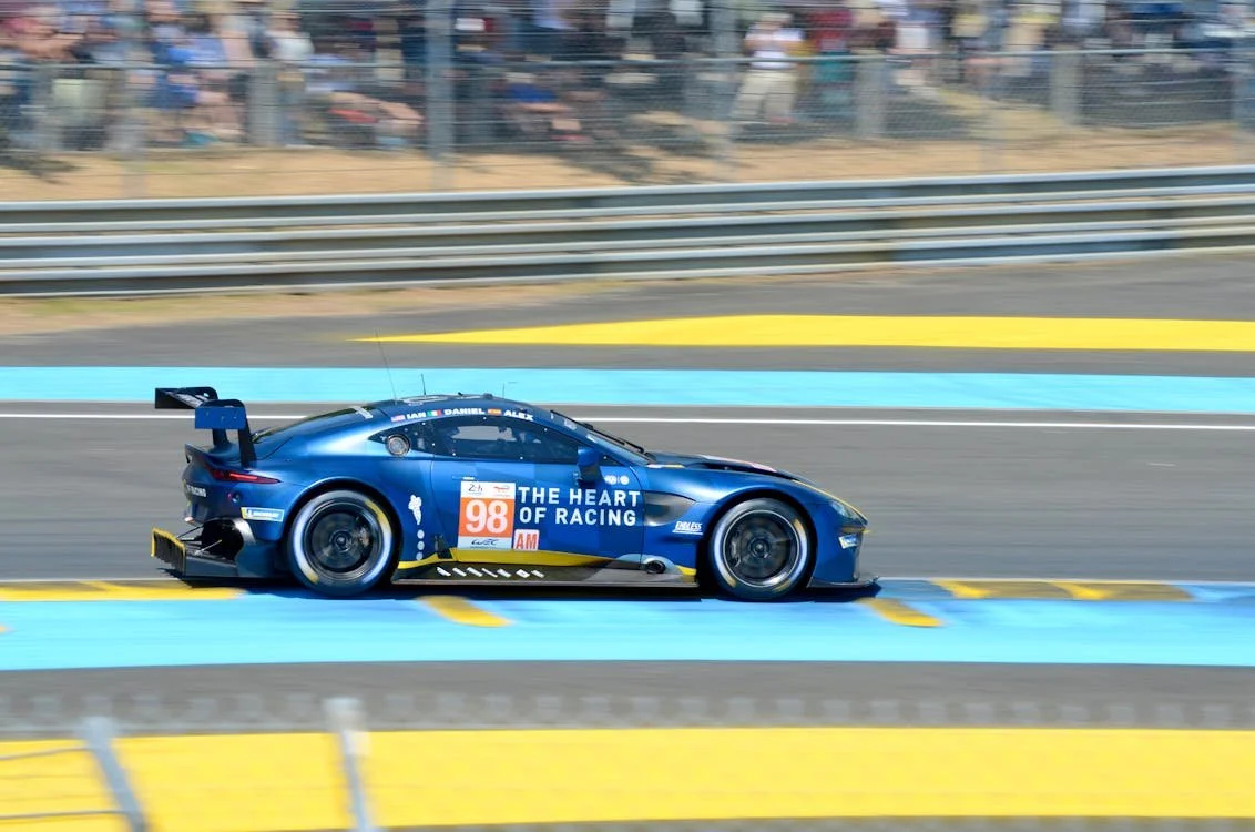 A blue racing car with number 98 on the side speeding on a race track.