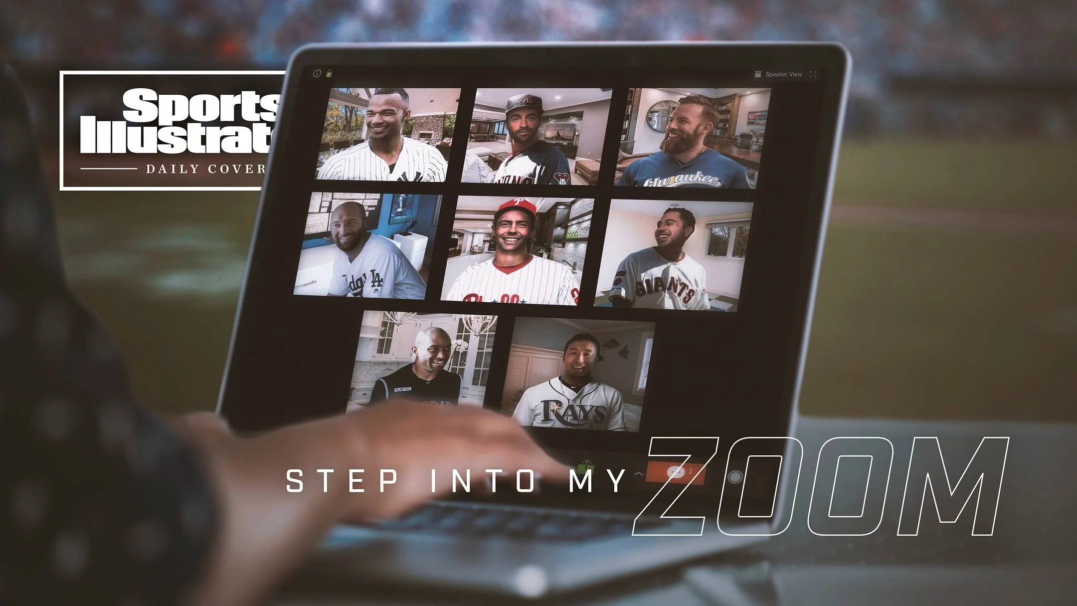 A person holding a tablet displaying a video call with six men, each wearing sports jerseys or casual clothes, all smiling, with a background hinting at a home or office setting. The tablet screen has the words 'STEP INTO MY ZOOM' at the bottom.