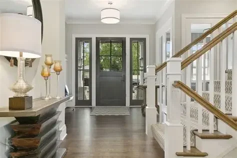 Entryway with a dark front door, large windows, white walls, and hardwood floors.