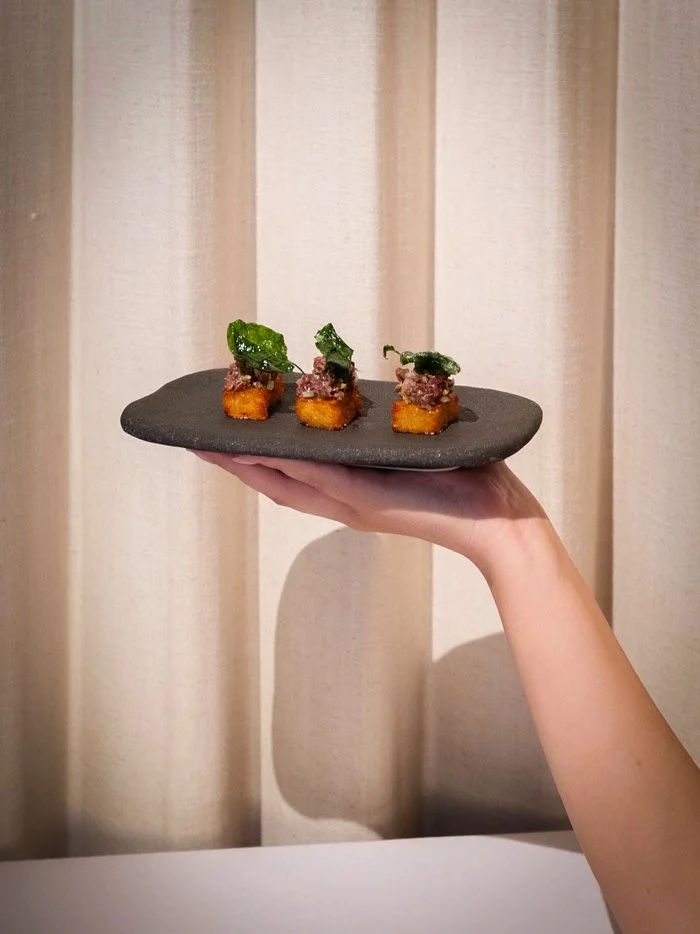 A hand holds a plate of Kangaroo Rosti from Aurora restaurant