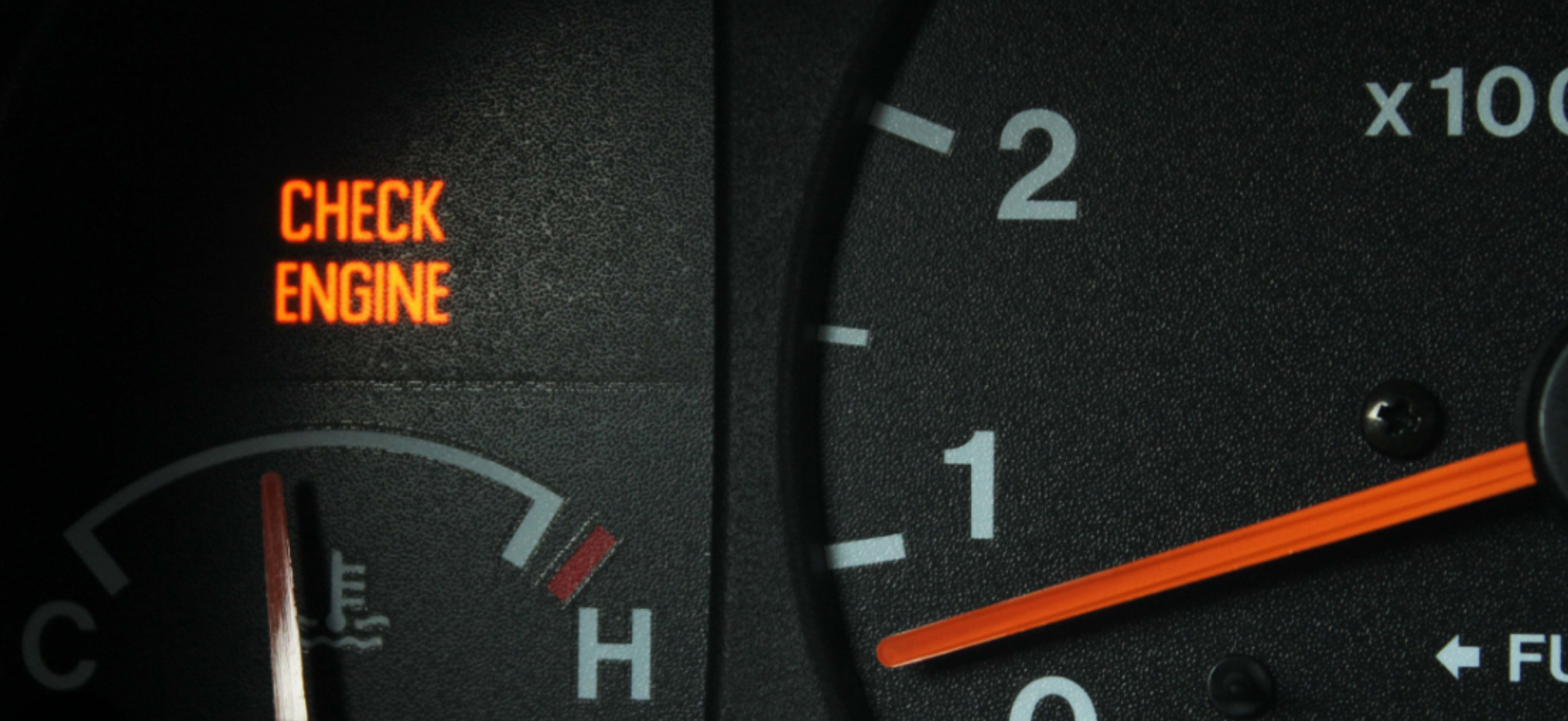 Close-up of a car dashboard showing a warning light with the text 'CHECK ENGINE' in red.