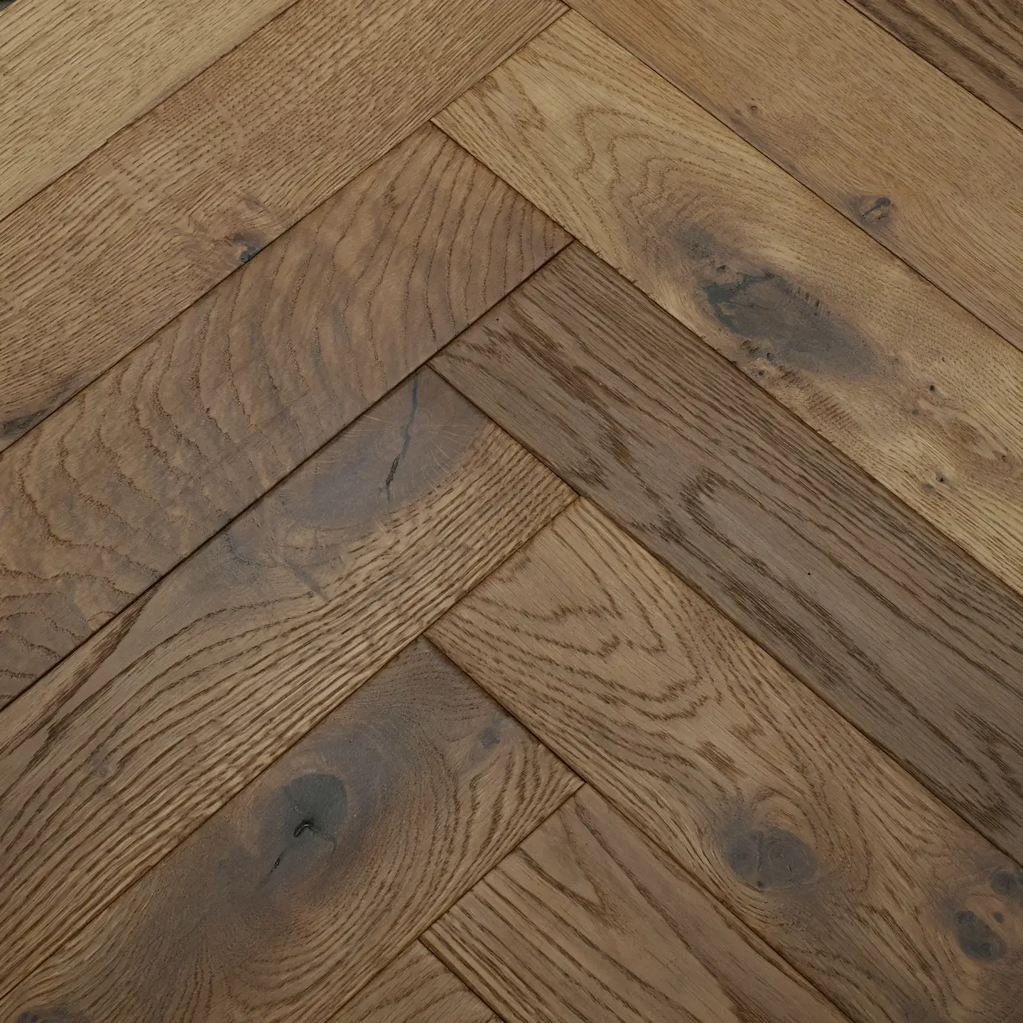 Close-up view of a wooden parquet floor with a herringbone pattern.