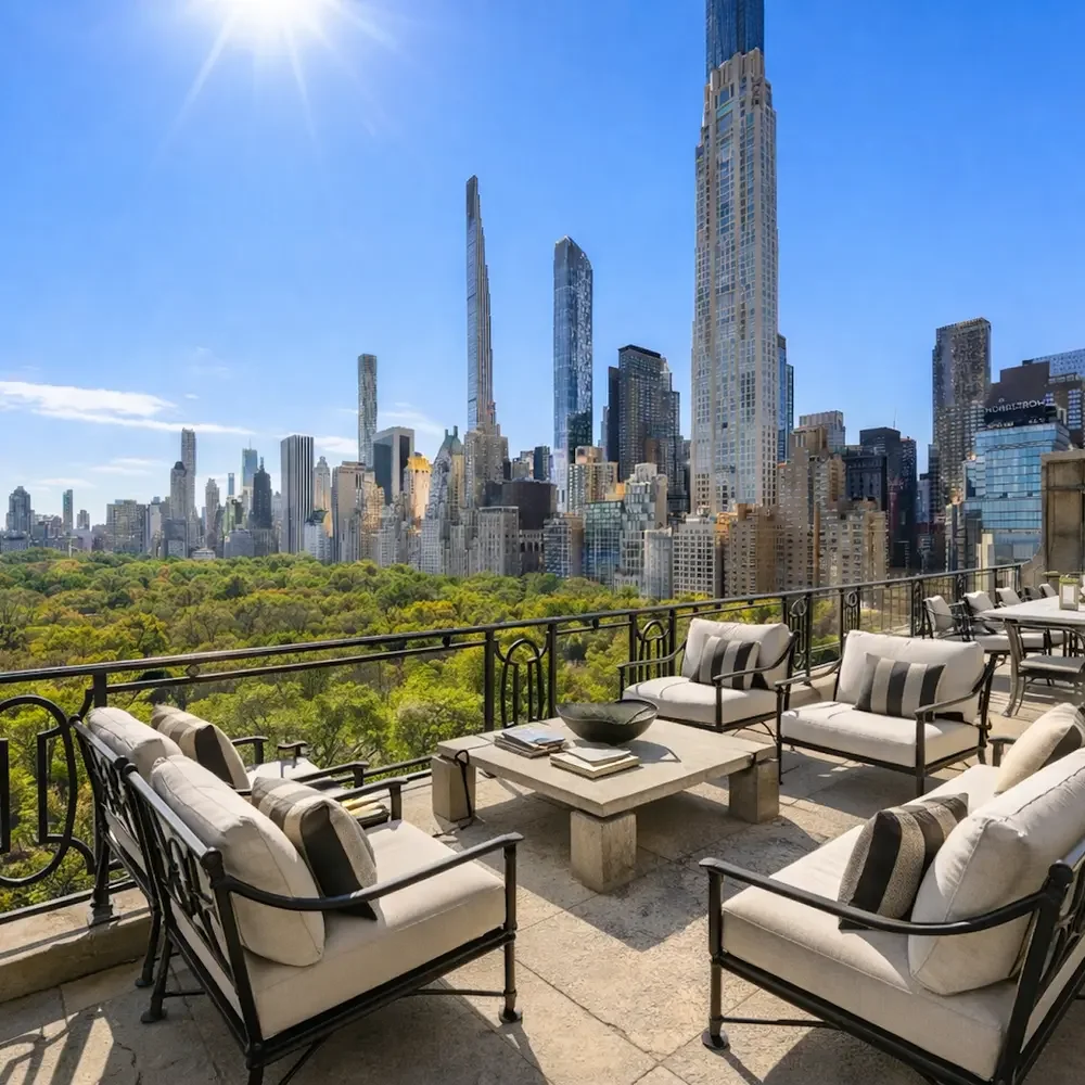 City skyline view from a balcony with outdoor furniture and a park with green trees in the foreground on a sunny day