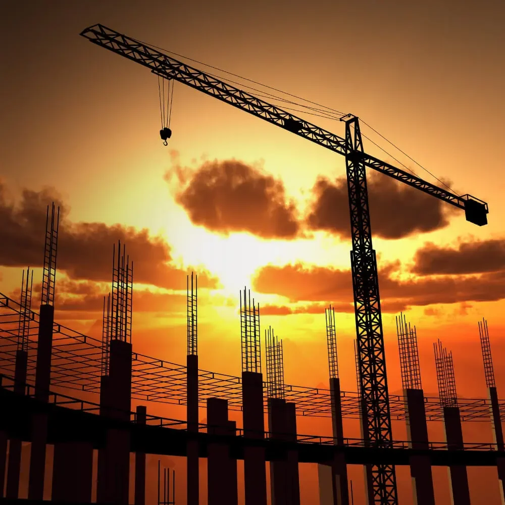 Construction site with a tower crane and ongoing building framework at sunset.