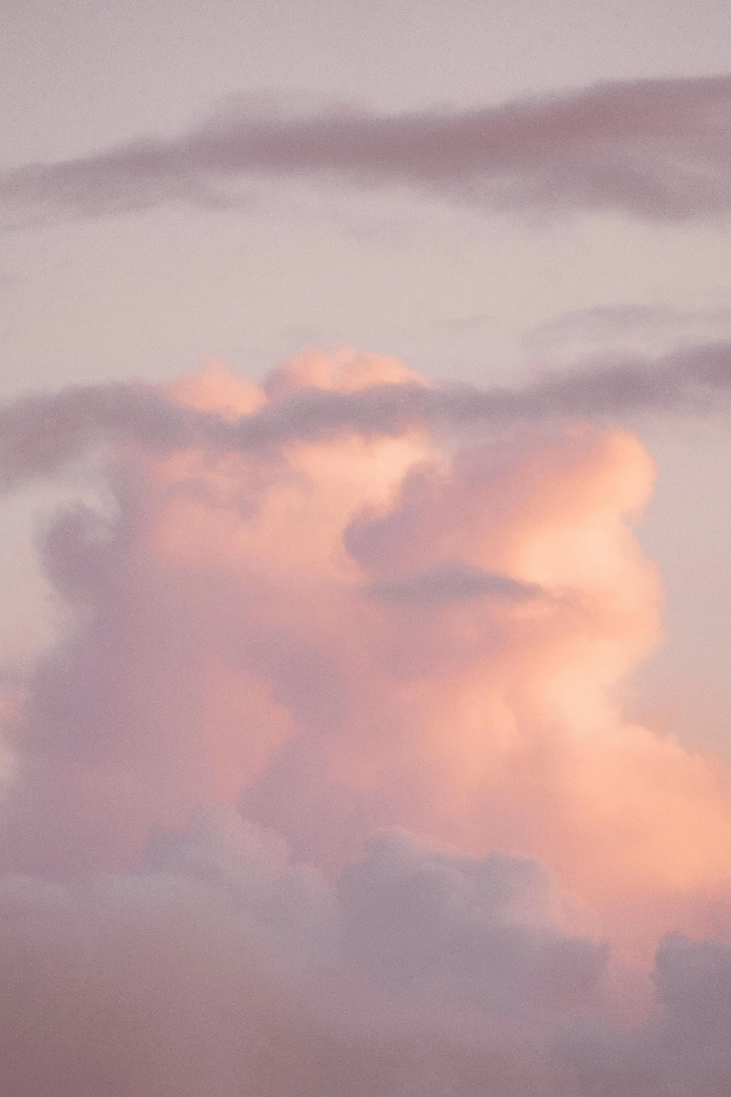 A pastel-colored sky with soft pink, purple, and peach clouds at dusk.