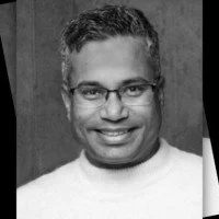 Schwarz-Weiß-Foto eines lächelnden Mannes mit Brille und kurzhaarigem Haar
