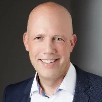Porträt eines lächelnden Mannes in formeller Kleidung, dunkler Hintergrund
