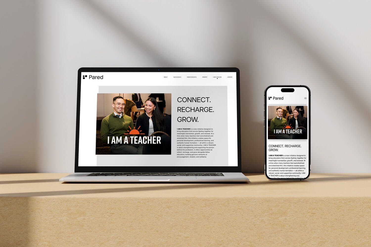 A laptop and smartphone displaying the same website titled 'Pared,' featuring a photo of two smiling people and the text 'Connect. Recharge. Grow.' on a light-colored table with a plain beige background.
