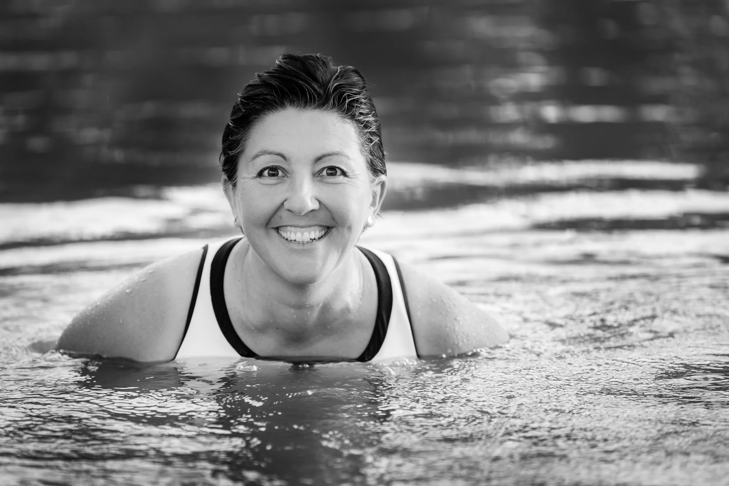 Mardie standing in the water up to her shoulders in the Murray River, with wet short dark hair, smiling.