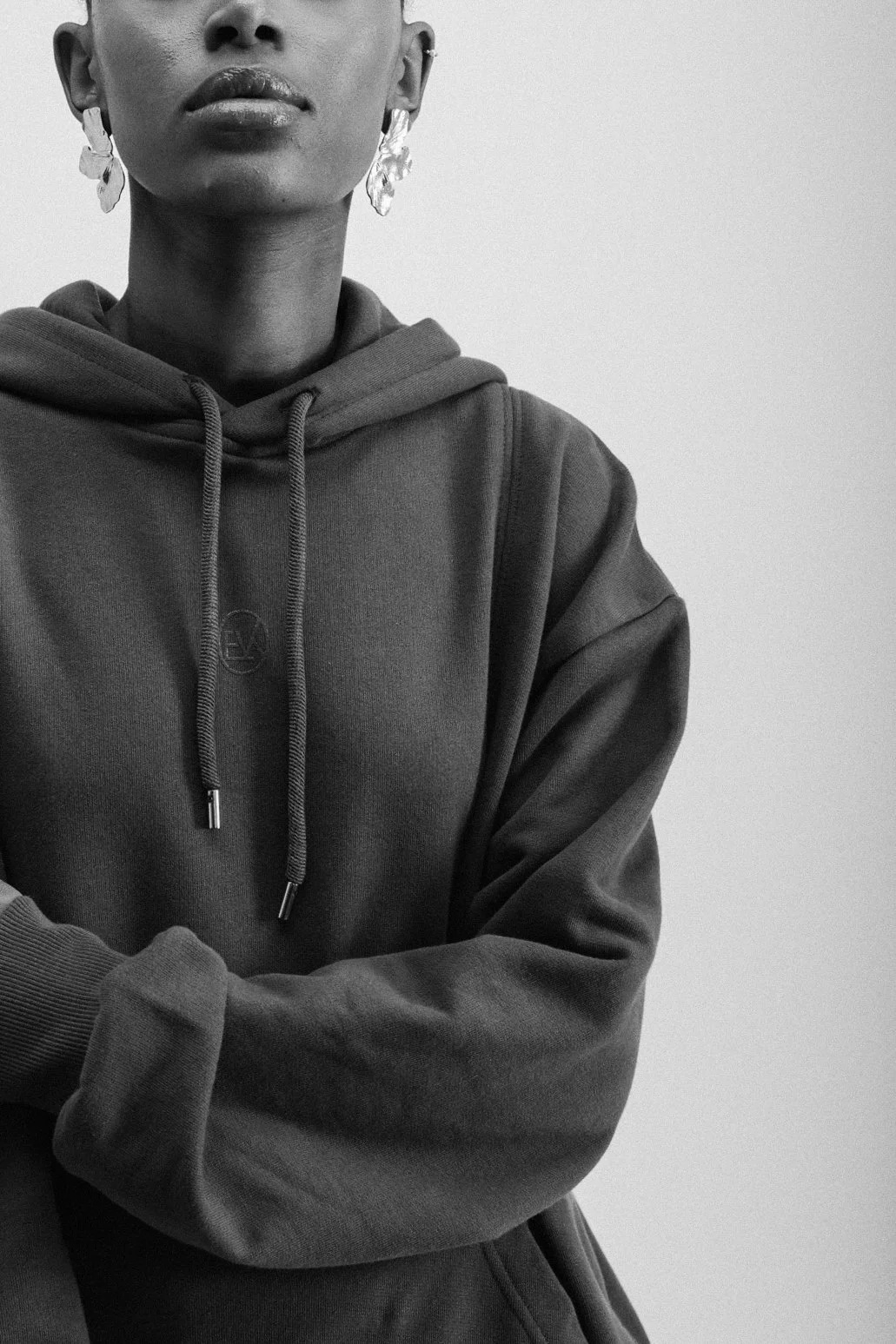 Close-up of a person wearing a hoodie, with their face partially visible and lips slightly parted, against a plain background.