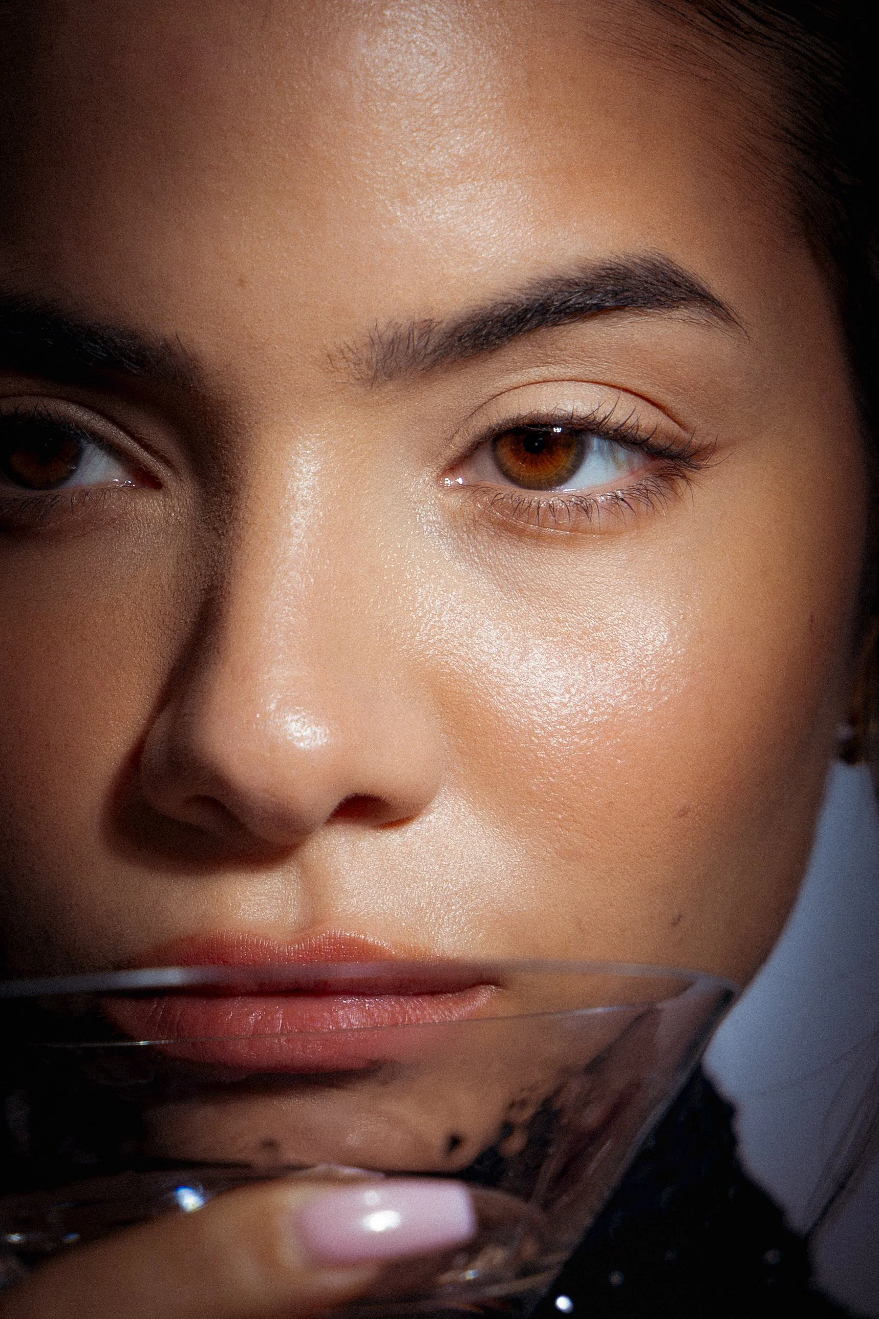 Close-up of a woman's face, showing her right eye, eyebrow, and part of her nose and lips with smooth skin and makeup.