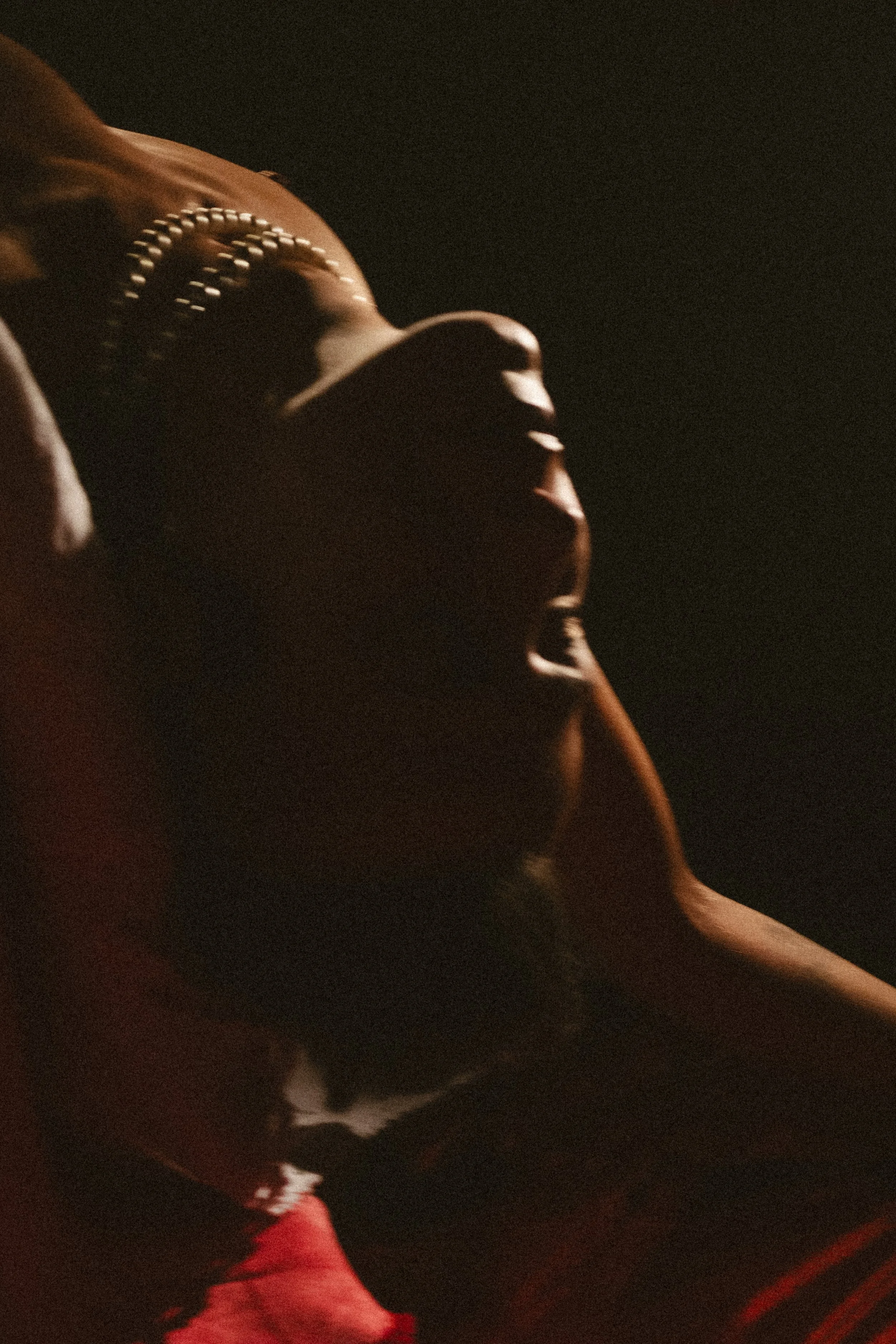 Close-up of a person wearing a brown hat with a pearl band, taken in low light.