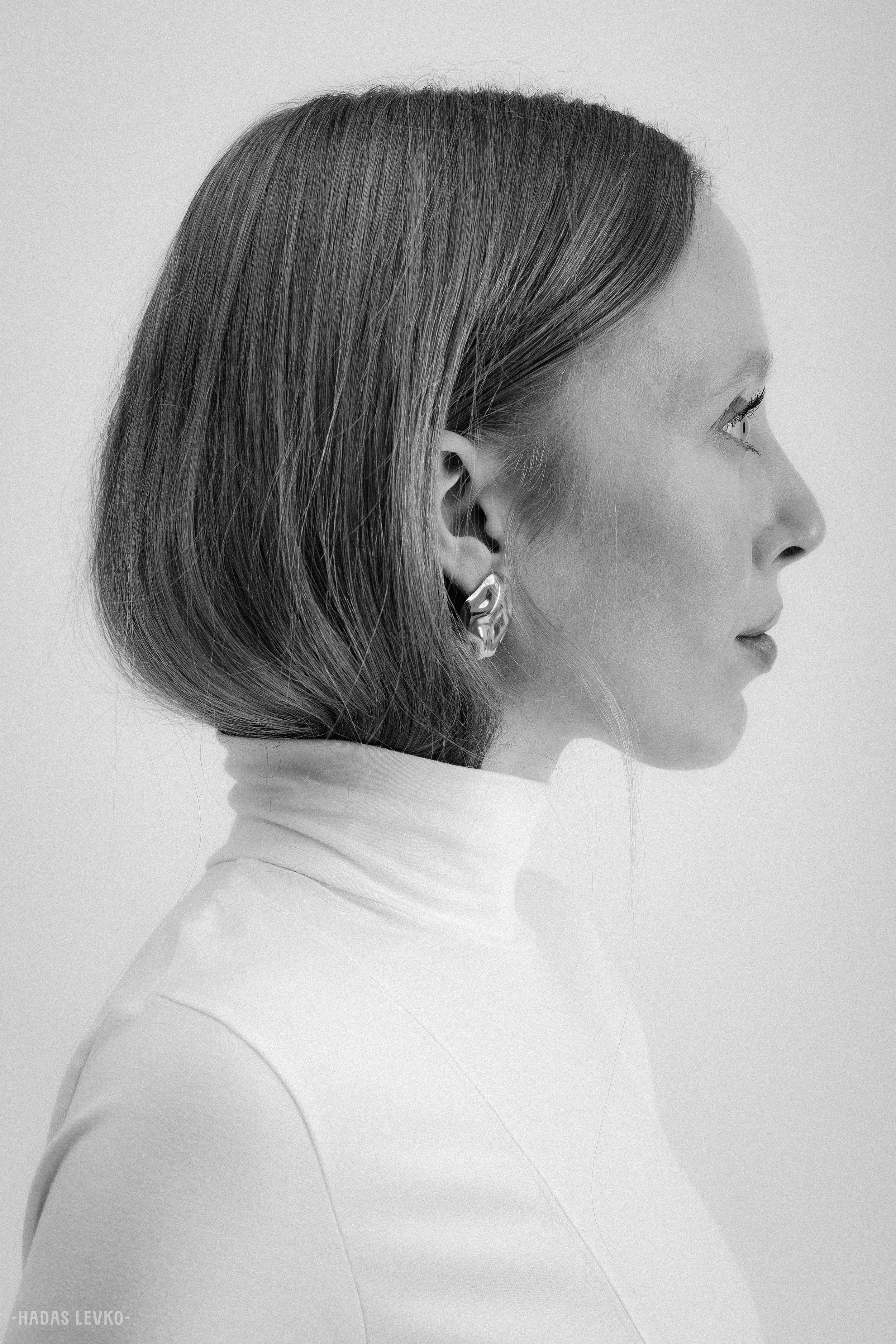 Profile side view of a woman with short hair, wearing a turtleneck and an earring, in black and white.