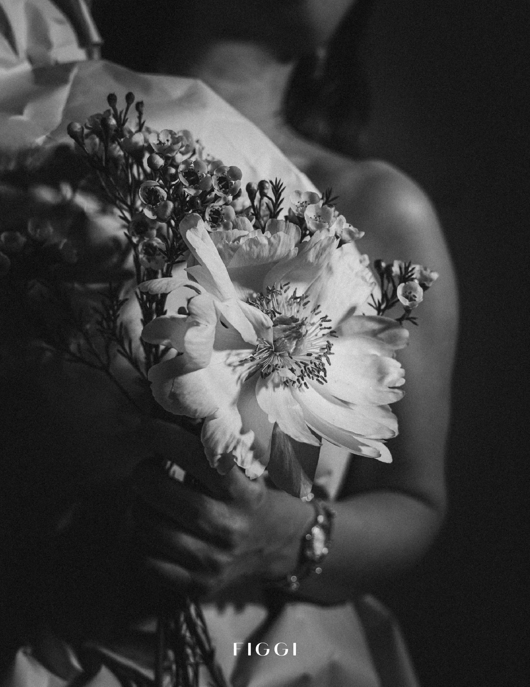 Close-up black and white photo of a bouquet of flowers, including a peony and small blossoms, with the word 'FIGGI' at the bottom.