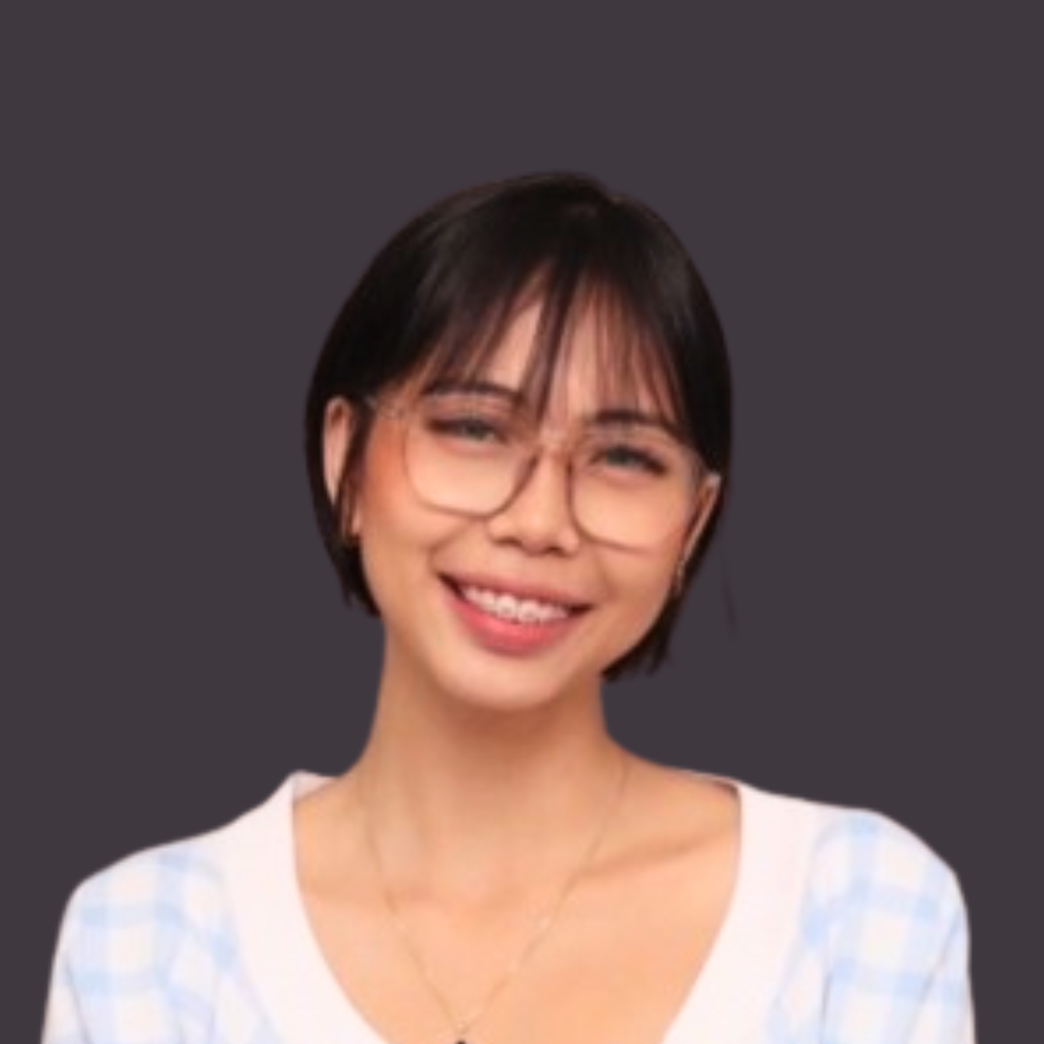 A woman with short dark hair, wearing glasses, smiling in front of a gray background.