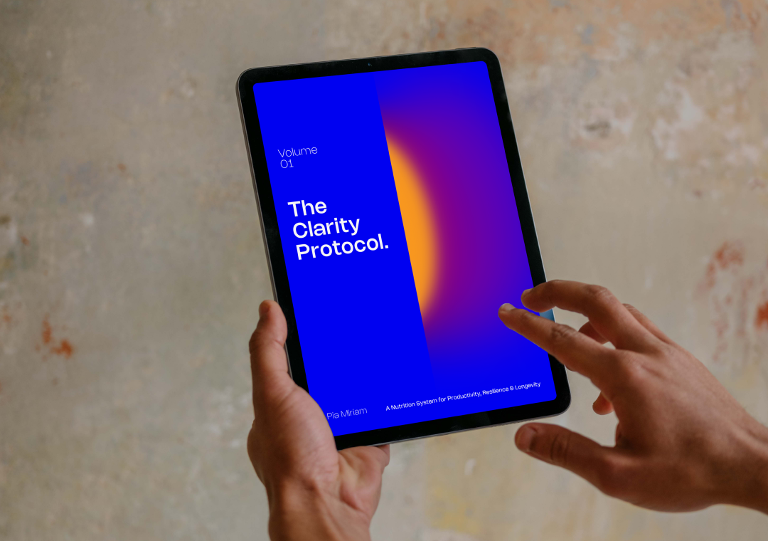 Persona sosteniendo una tableta con la portada de un libro digital titulado "The Clarity Protocol" y un fondo de pared de cemento.
