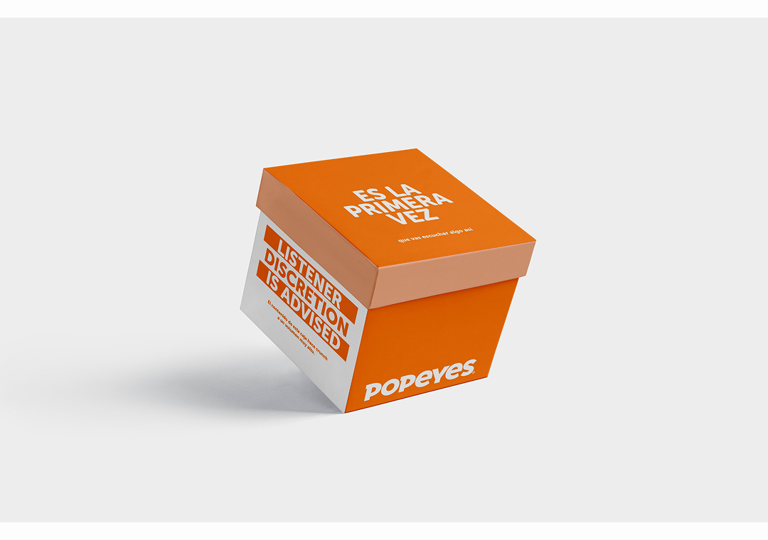 Cajita de papel de Popeyes con advertencia de advertencia y texto en inglés y español