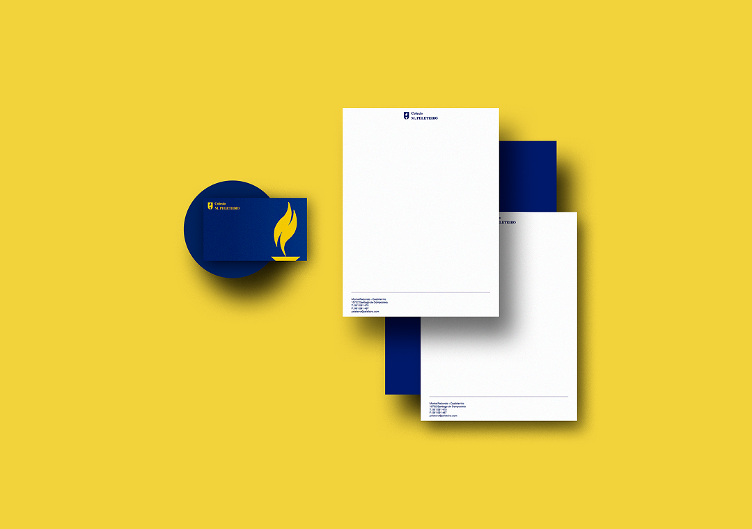 Material de papelería con el logo de un libro y una llama en color amarillo sobre fondo azul, sobre una superficie amarilla.