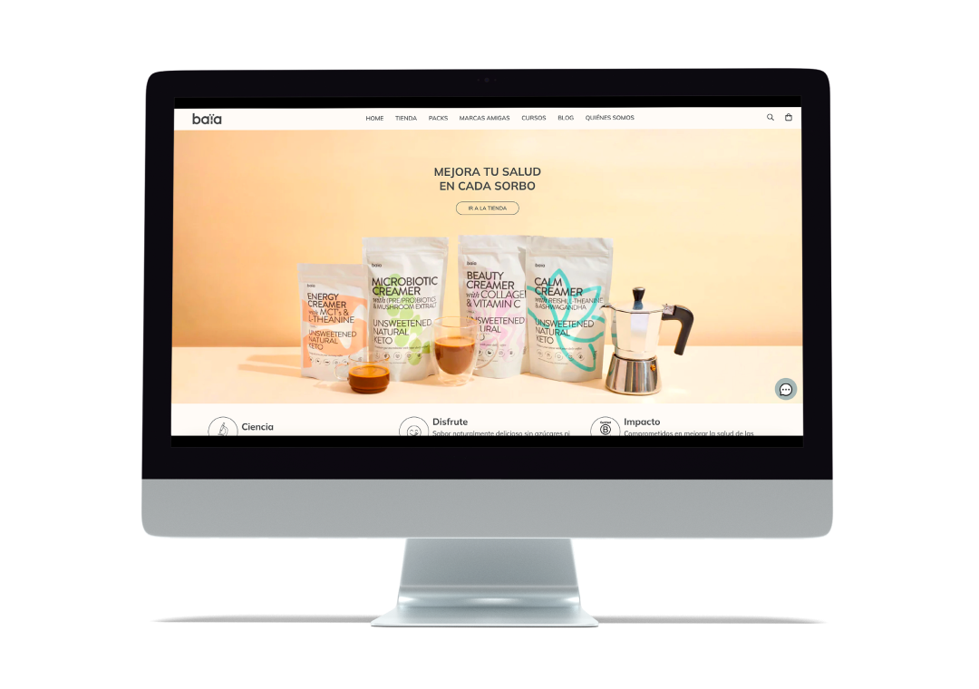 Pantalla de computadora con página web que muestra productos en paquetes para mejorar la salud en un fondo naranja y una tetera de café