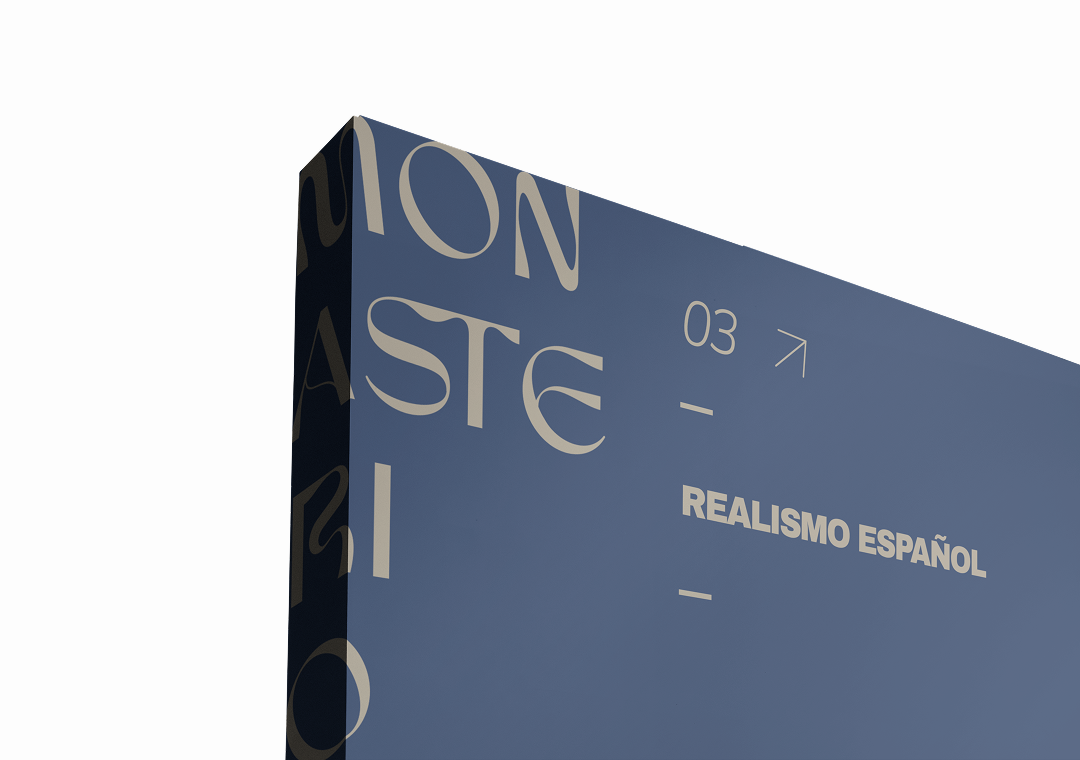 Vista parcial de una cartelera azul con texto en español sobre realismo español, con el número 03 y una flecha hacia la derecha.