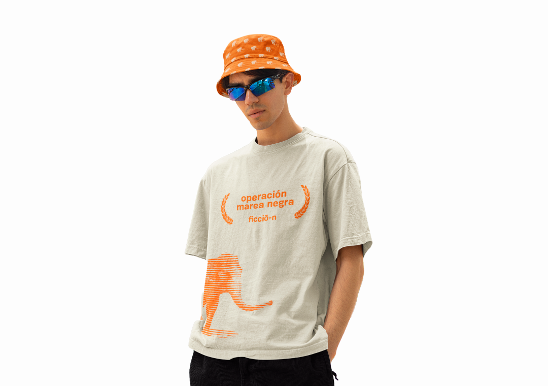 Joven con camiseta beige con texto en naranja y dibujo de un león en la parte inferior, usa gafas de sol azules y gorra naranja con puntos blancos.