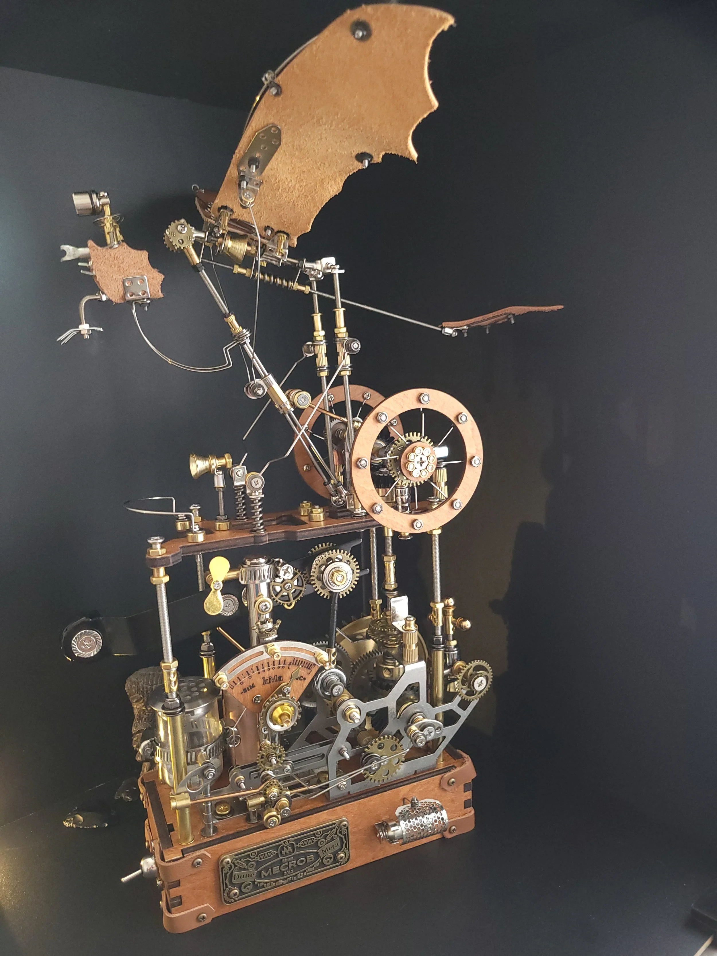 A vintage mechanical Leonardo da Vinci exhibit with intricate gears, levers, and a wooden base, showcasing steampunk-style craftsmanship.