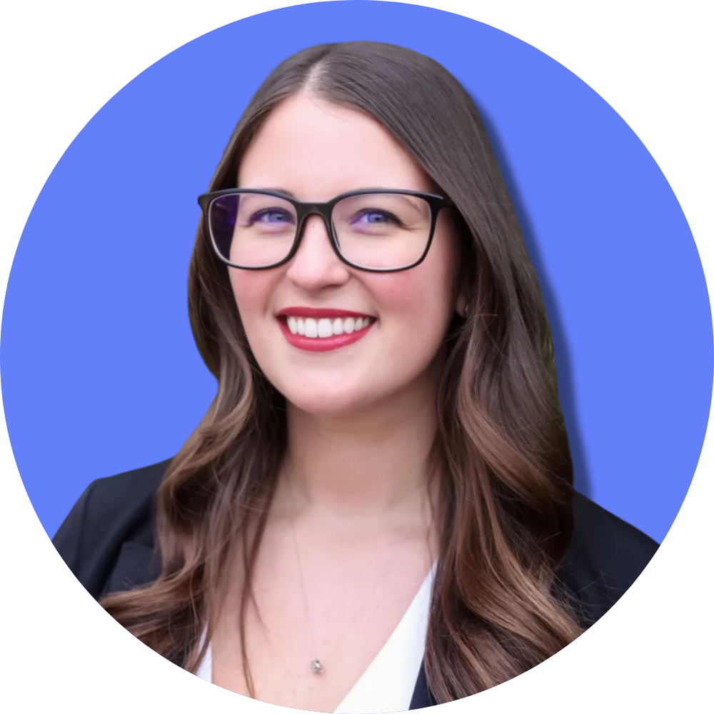 A woman with long brown hair, wearing glasses, a black blazer, and a white top, smiling against a blue abstract background.