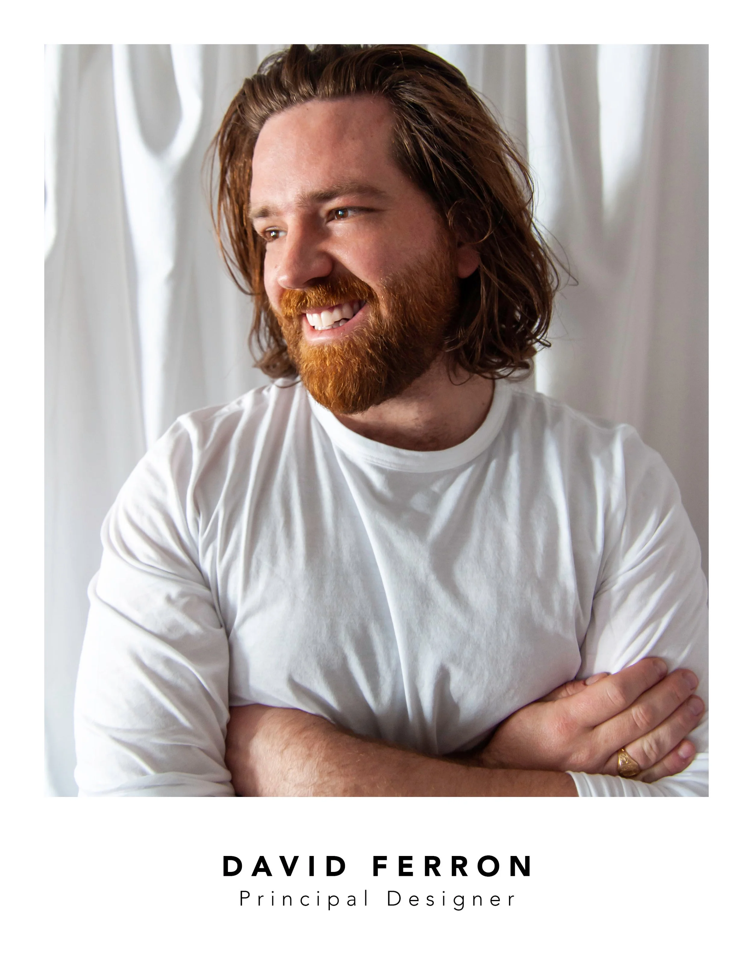 A man with red hair and beard, smiling, wearing a white shirt with his arms crossed. Background has white curtains. Text on image says 'David Ferron, Principal Designer'. Portrait image David Ferron, interior designer, Milford, New Jersey