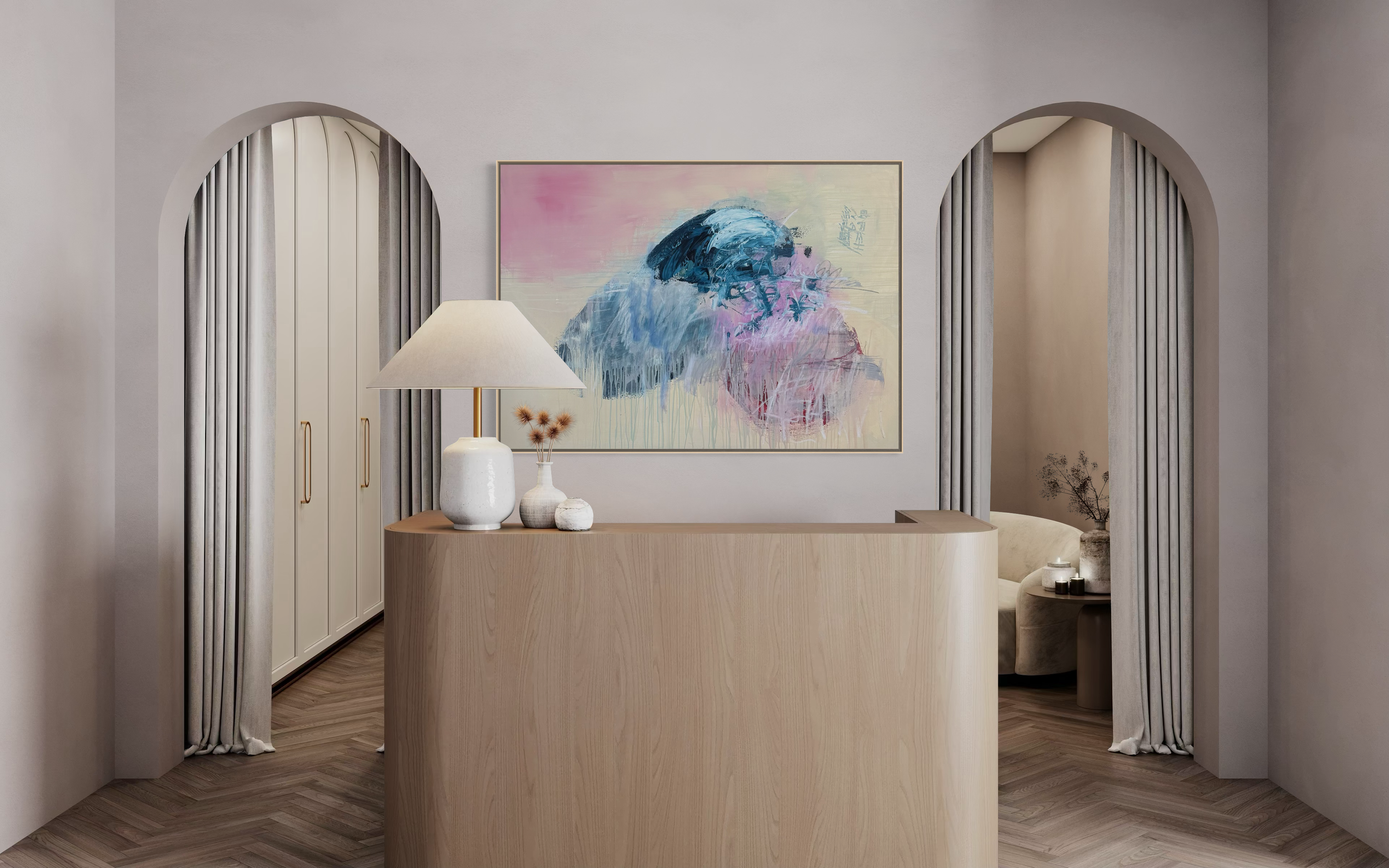 Interior of a modern living room with a light-colored curved wooden reception desk, abstract wall art, and decorative objects including a white table lamp and vases. Arched doorway openings with curtains frame the space.