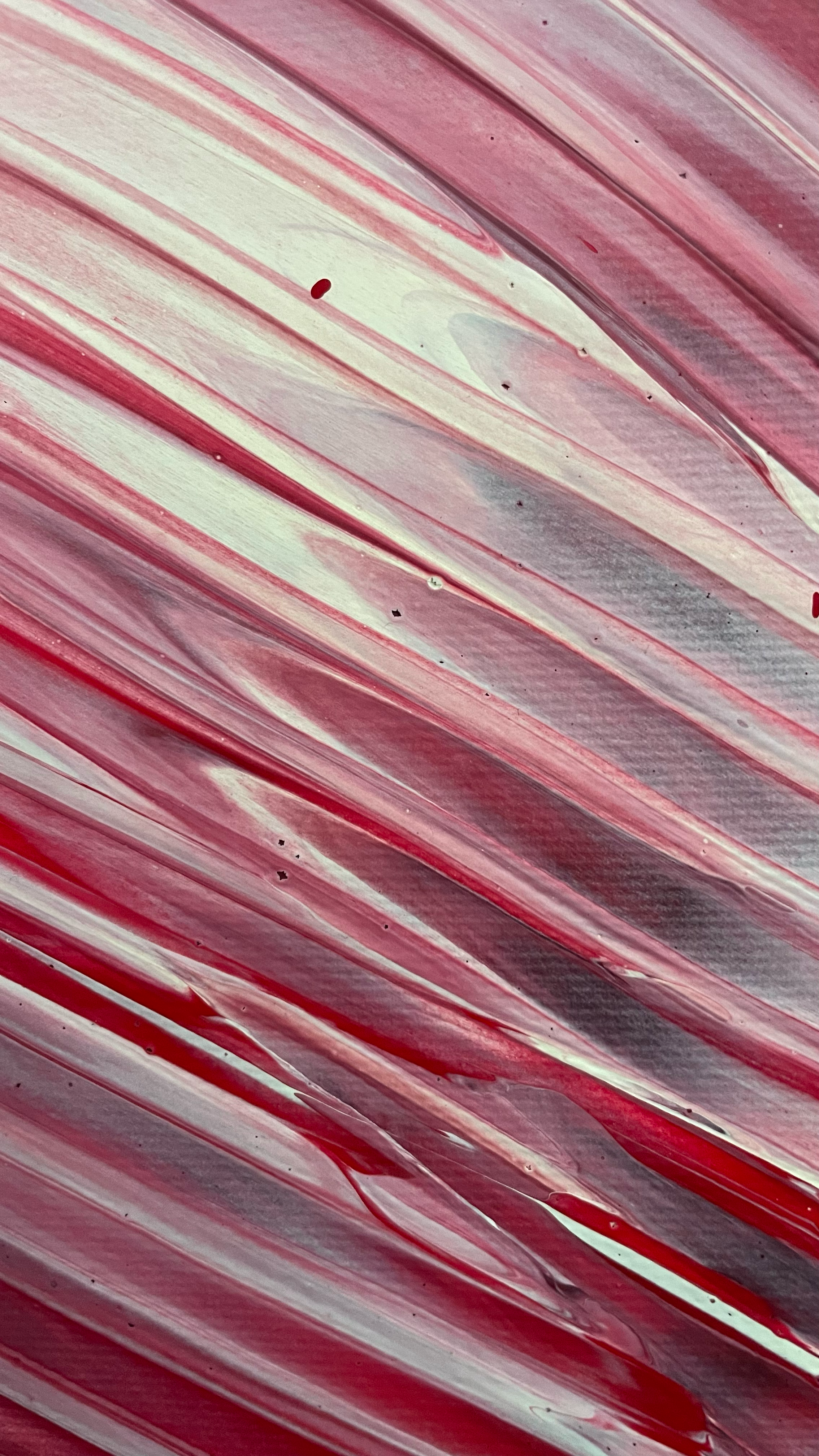 Close-up of a textured surface with swirling red, white, and gray paint.