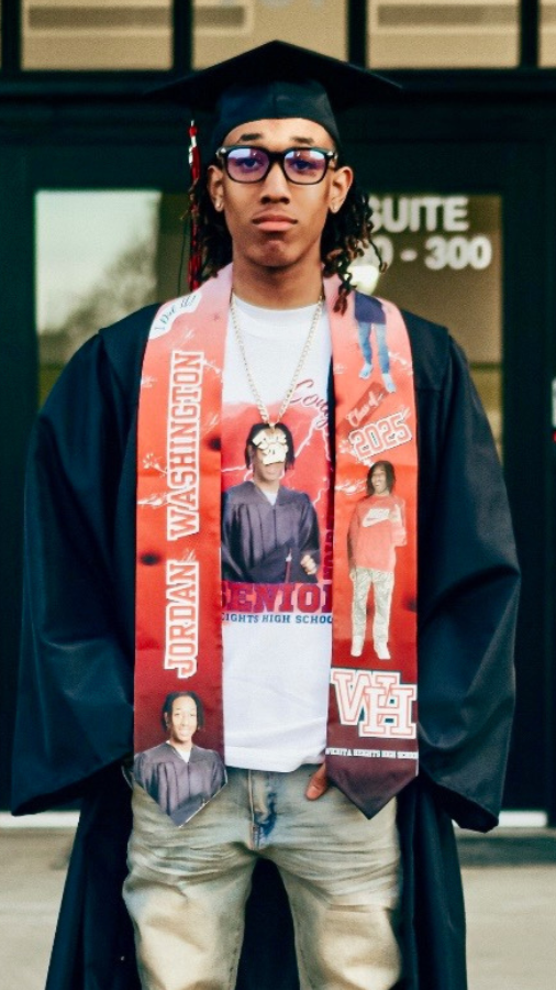 A young man in graduation cap and gown standing outdoors, wearing a sash with graduation-themed images and text, and a white T-shirt underneath.