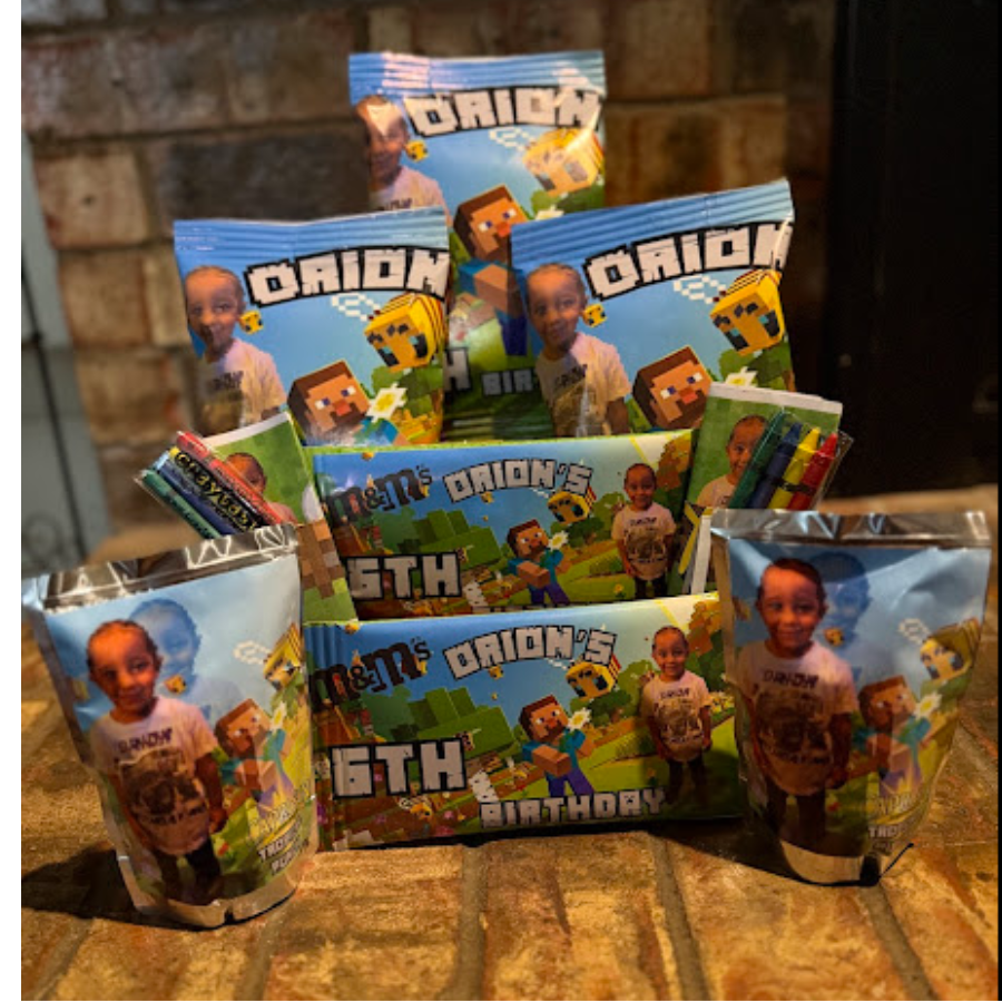 Collection of Minecraft-themed party favors including snack bags, and goodie bags with a child's photo and birthday message on the packaging, arranged on a brick surface.